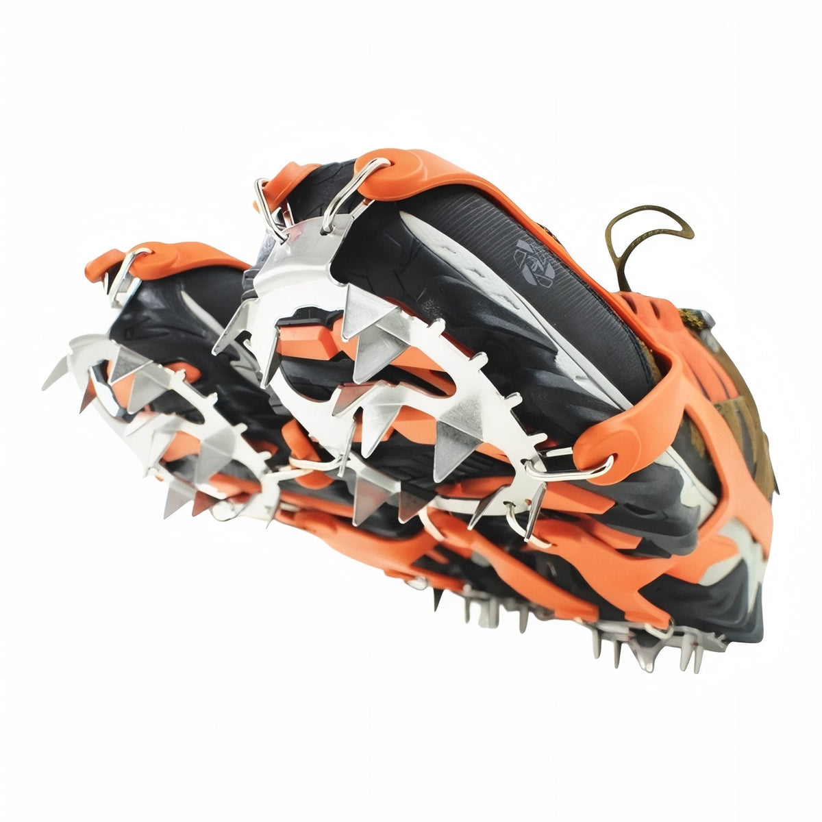 Orange crampons fitted on a hiking shoe seen from below, the spike plates covering the sole