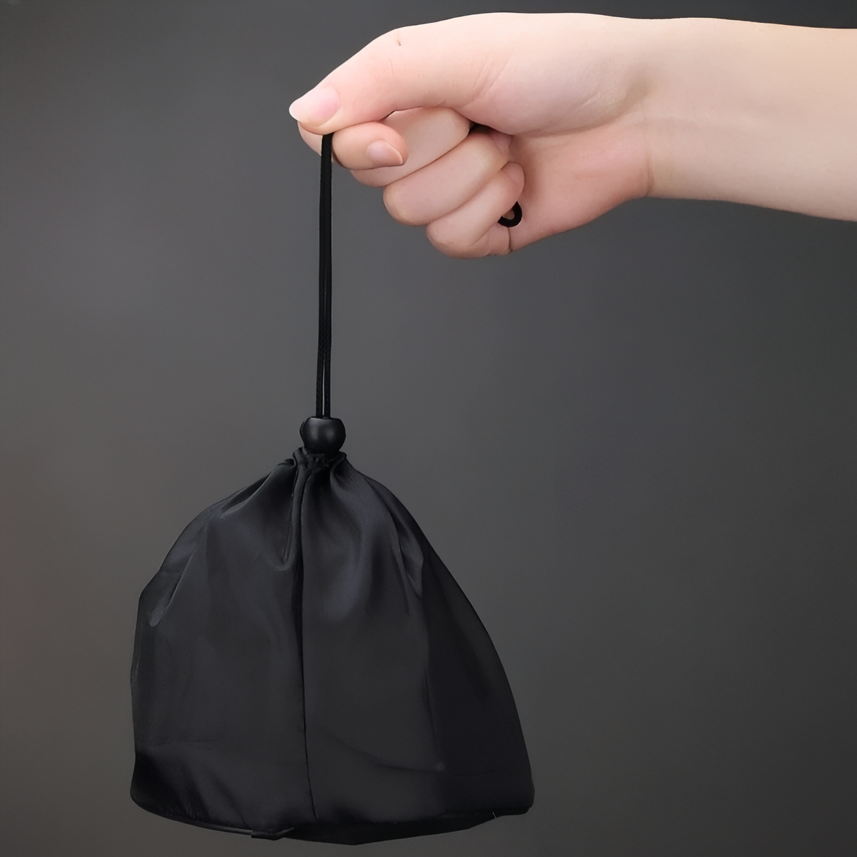 Hand holding the black drawstring storage bag for the folded stove