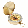 Gold-tone pocket compass open, showing the white degree bezel and the cream dial with a red and black compass rose