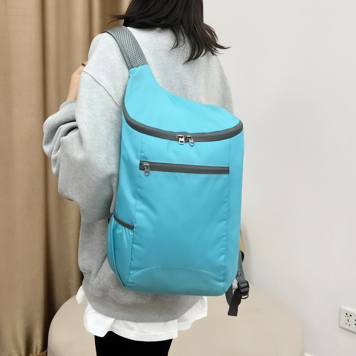 Woman carrying the sky blue packable daypack on one shoulder
