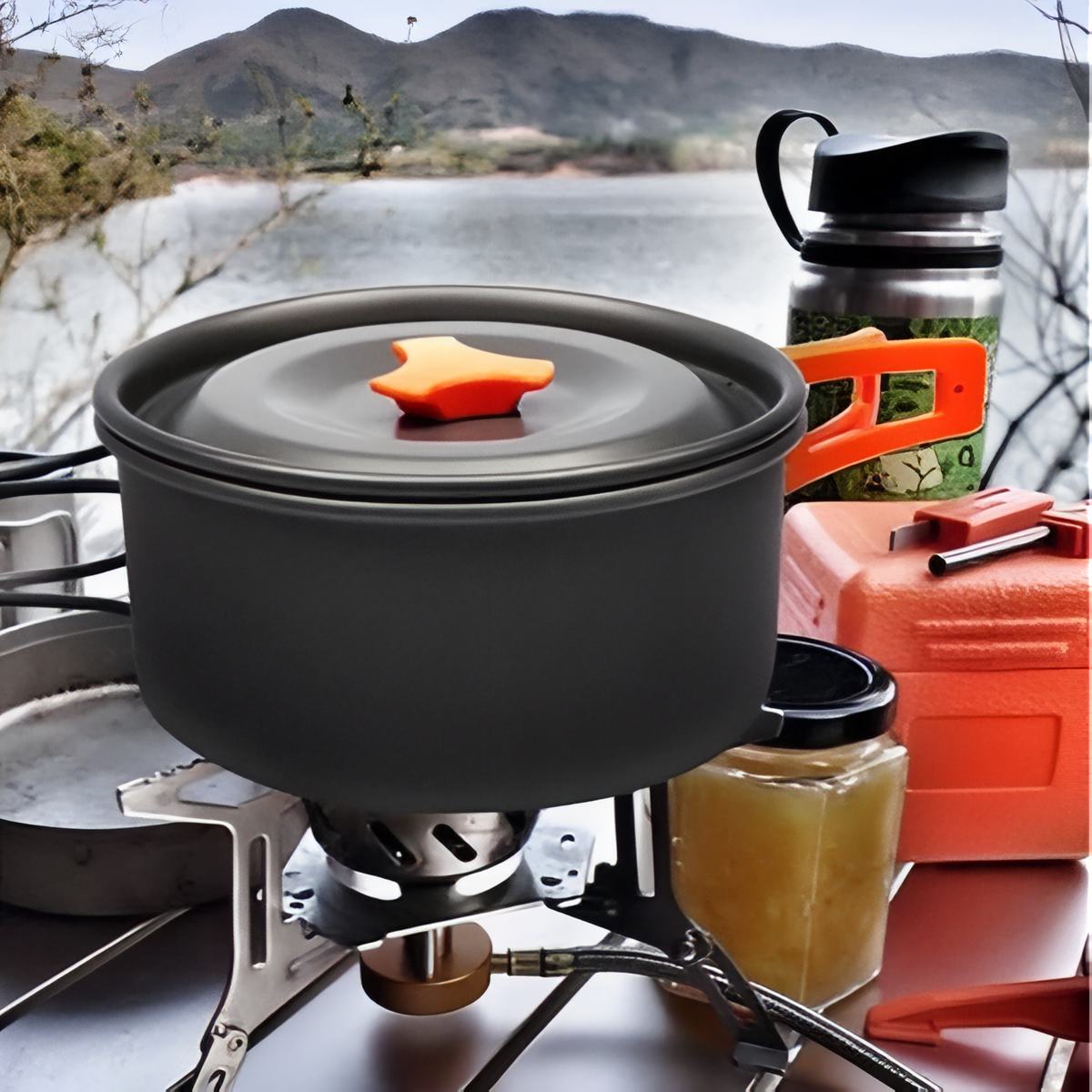 Pot with its lid on a camping stove by a lake