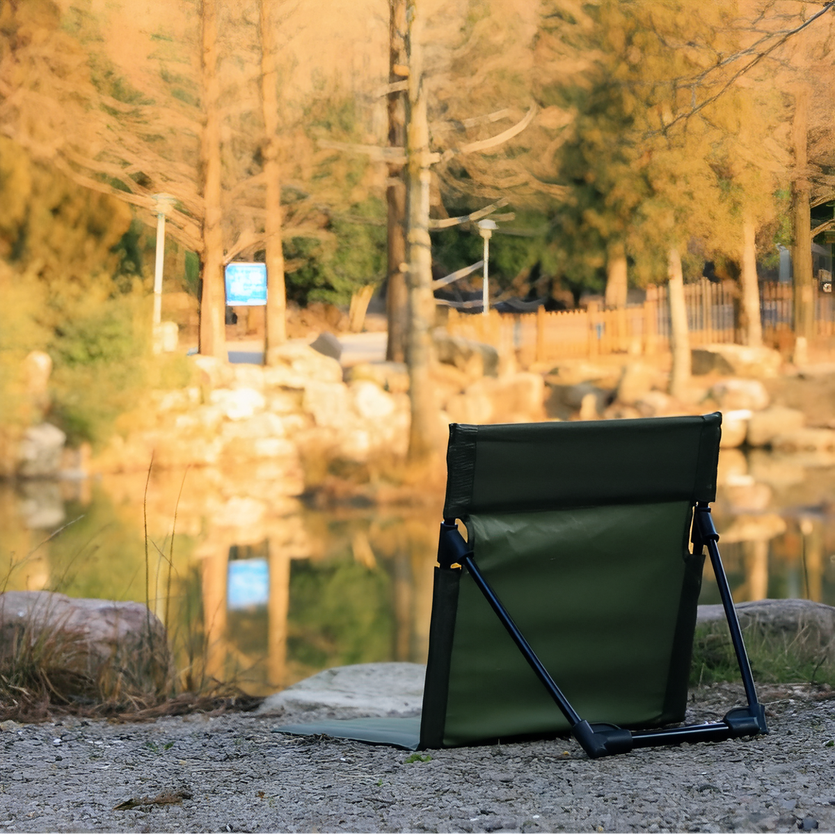 Dark green ground chair set up on a lakeside shore at sunset