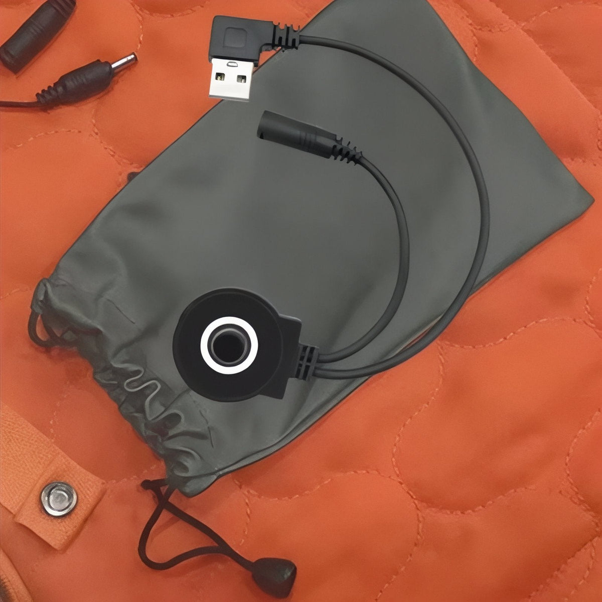 Close-up of the USB cable, the round controller button and the grey pouch on the orange pad