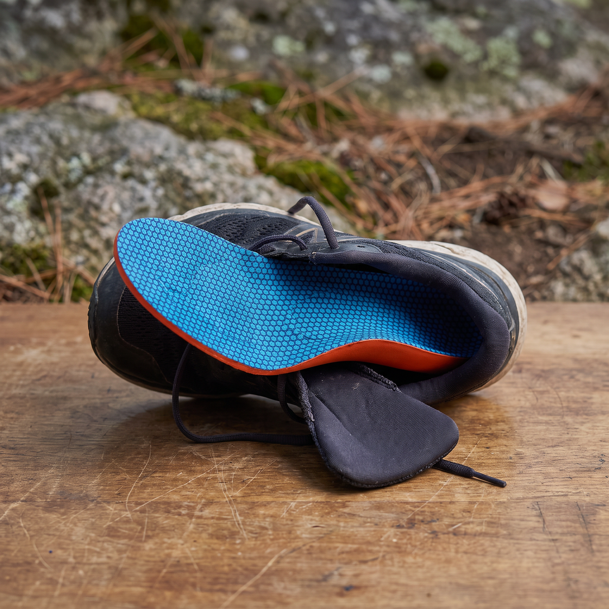 Arch-support insole placed in a dark walking shoe on a wooden table