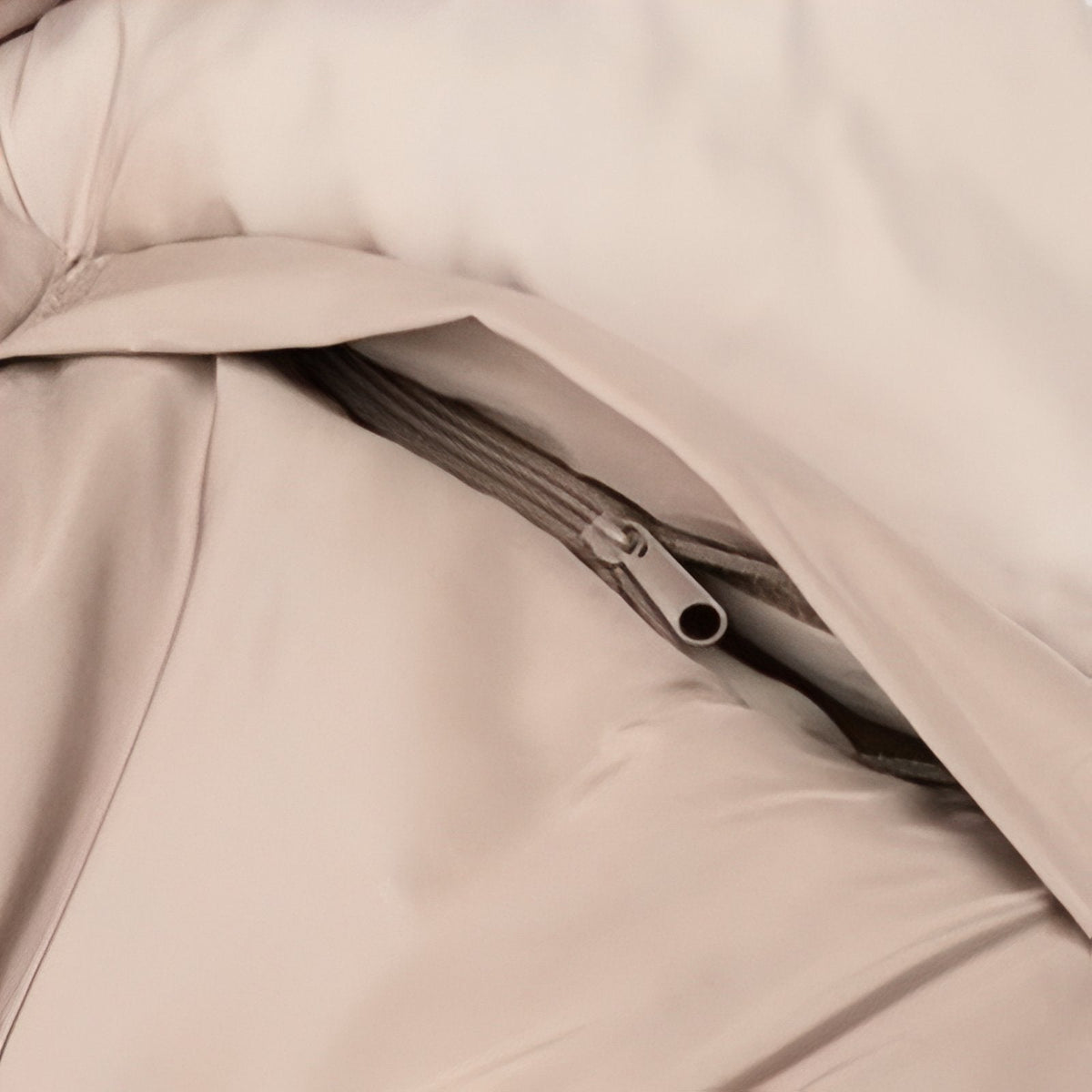 Close-up of a zipped arm opening in the side of the light beige sleeping bag