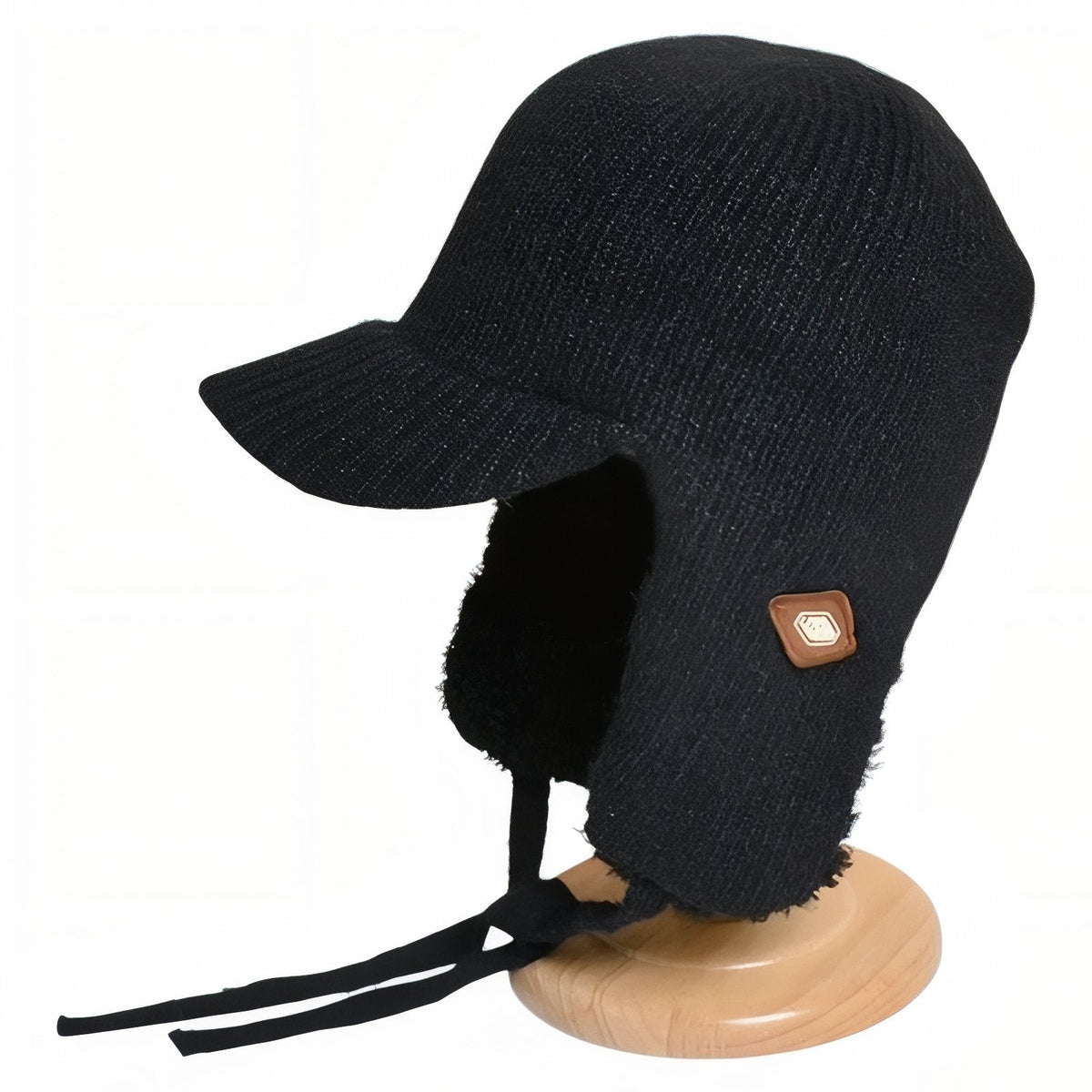 Black knitted trapper hat with plush ear flaps on a wooden hat stand
