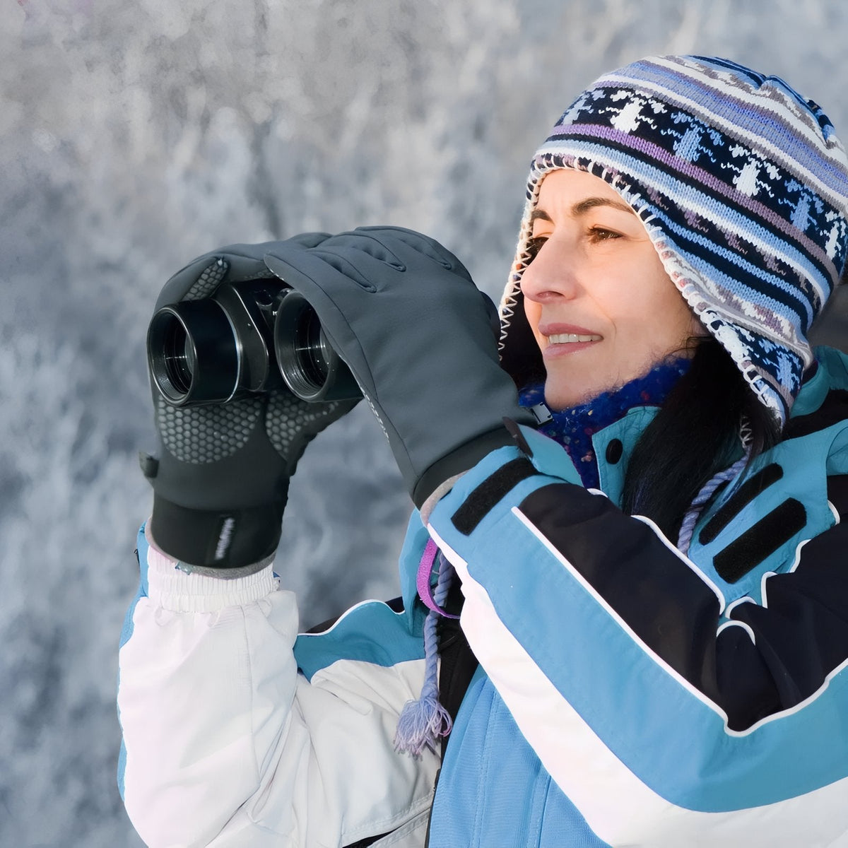 Woman in a ski jacket and knitted hat looking through binoculars, wearing slate grey hiking gloves with a silicone grip palm