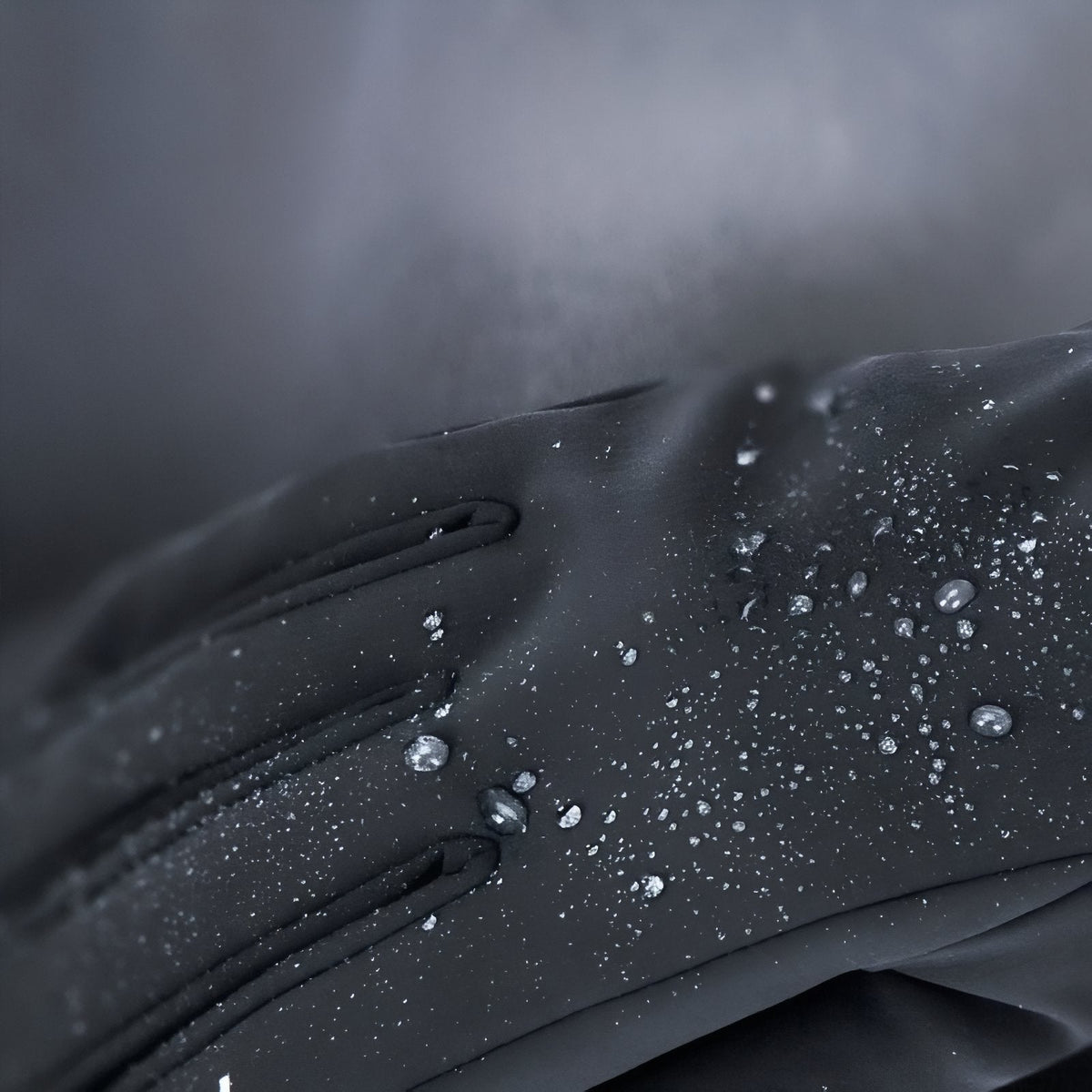 Water droplets beading on the back of a dark hiking glove