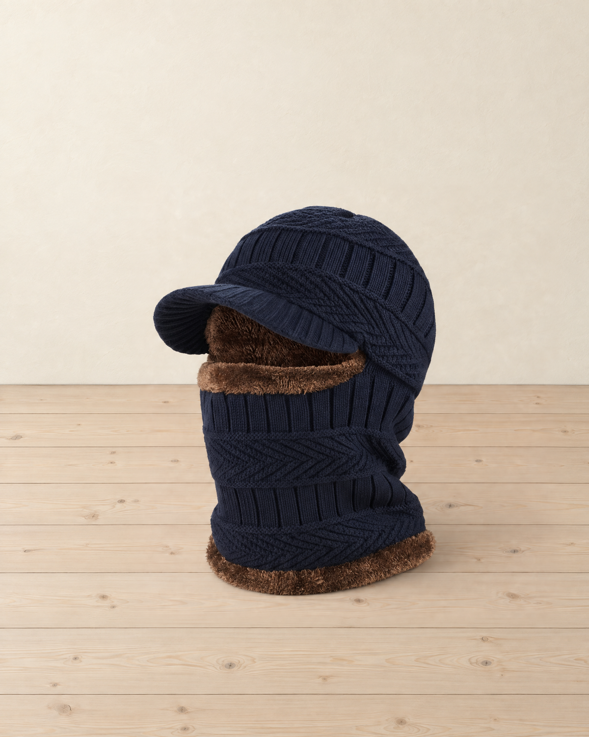 Navy blue knitted balaclava with a short brim and brown plush lining standing on pale pine floorboards
