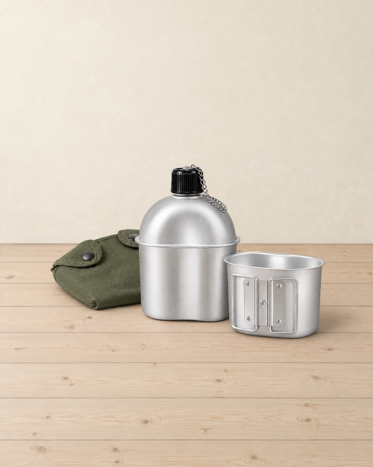 Aluminium canteen with a chained black cap, its cup and olive-green cover on pale pine floorboards