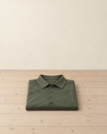 Army green men's short-sleeved hiking polo shirt folded on a pale pine floor, showing the flat collar, the three-button placket with its small loop and the sleeve pocket edge