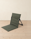 Olive green folding ground chair with a padded seat and a backrest on black side frames, on pale pine floorboards