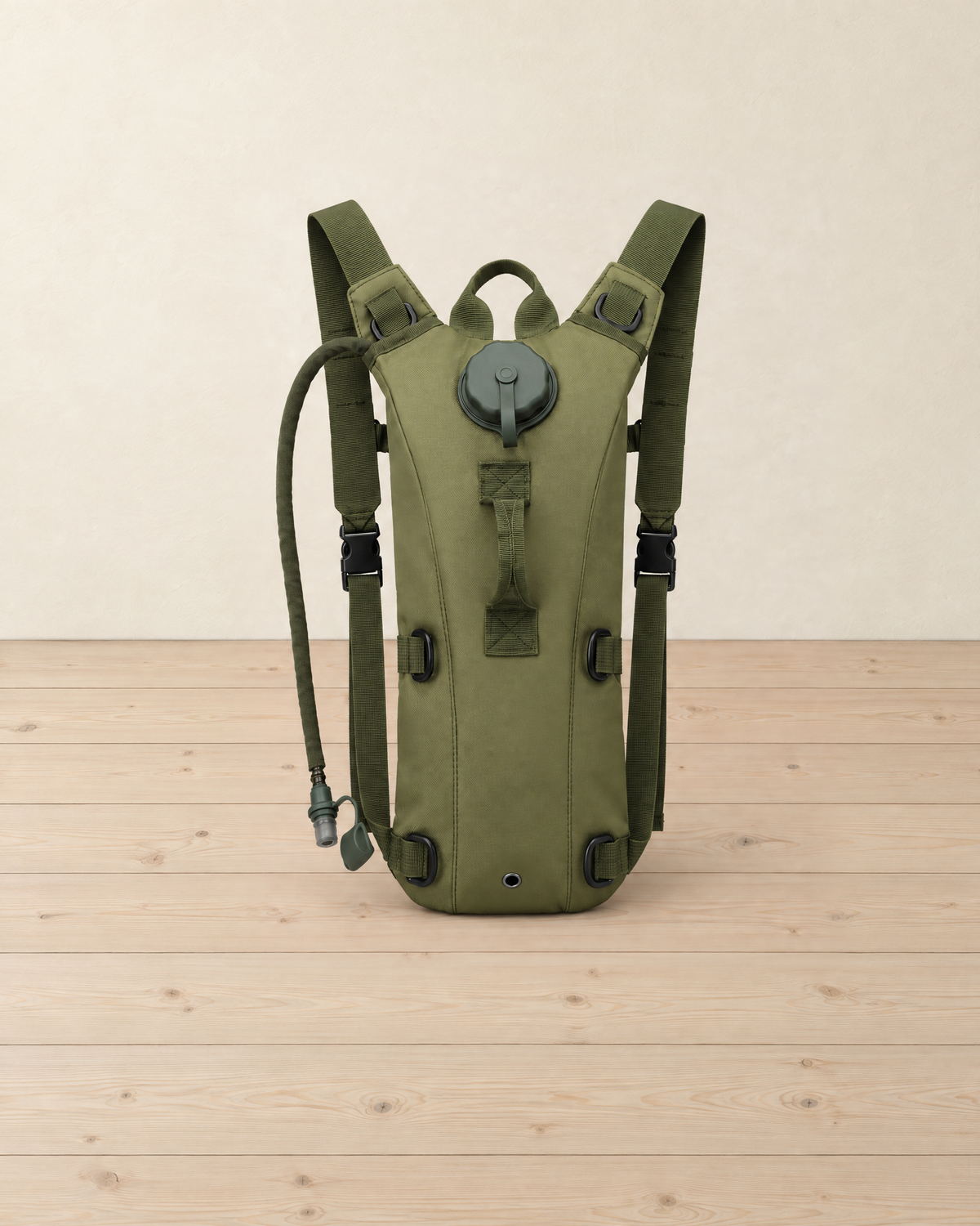 Olive green 3 litre hydration pack with a drinking tube standing on pale pine floorboards