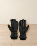 Pair of black fleece-lined winter hiking gloves with a zip pocket, wrist strap and knitted cuffs, one back up and one palm up on a pale pine floor