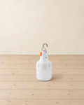 White rechargeable LED bulb lantern with a steel hanging hook standing on pale pine floorboards