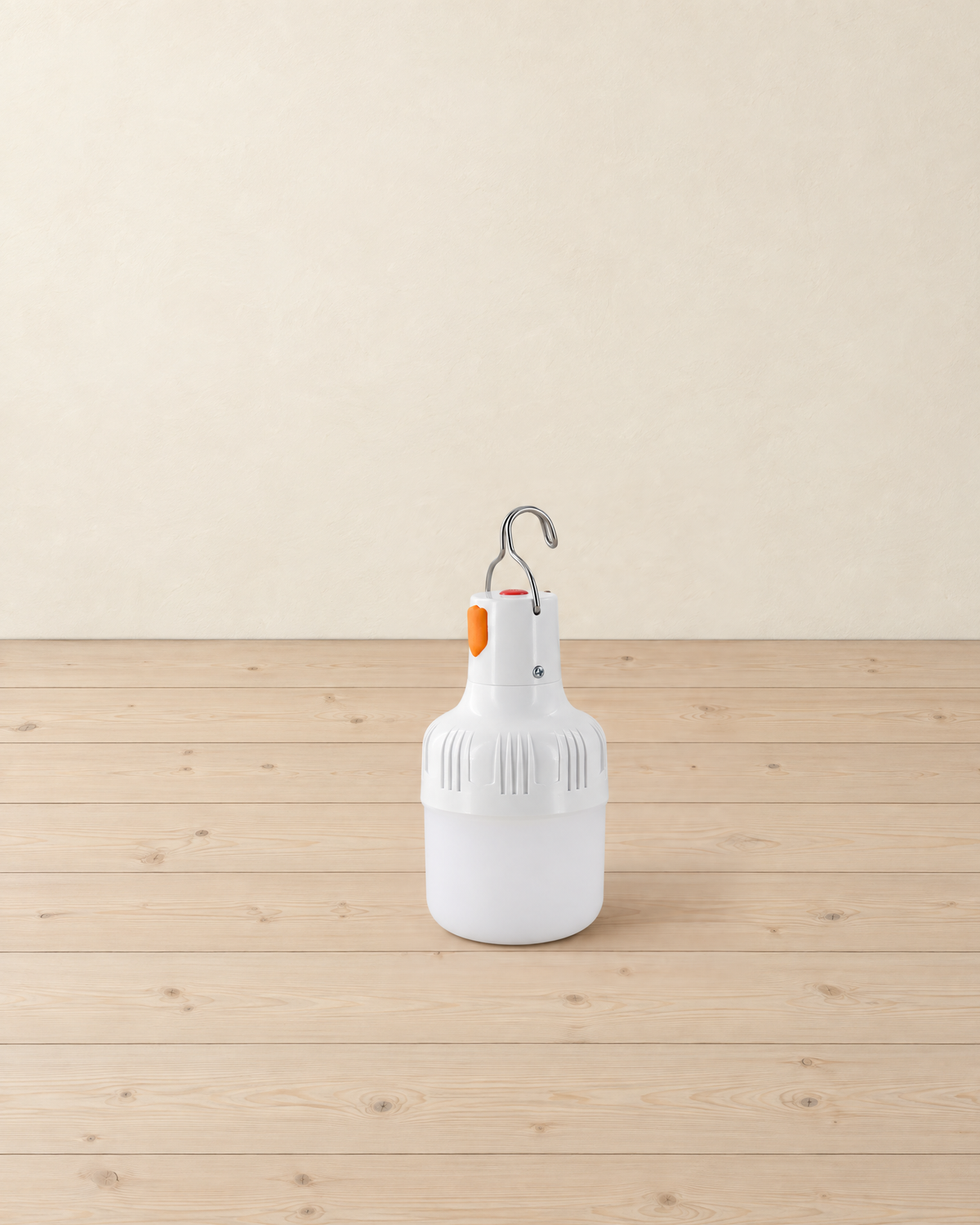White rechargeable LED bulb lantern with a steel hanging hook standing on pale pine floorboards