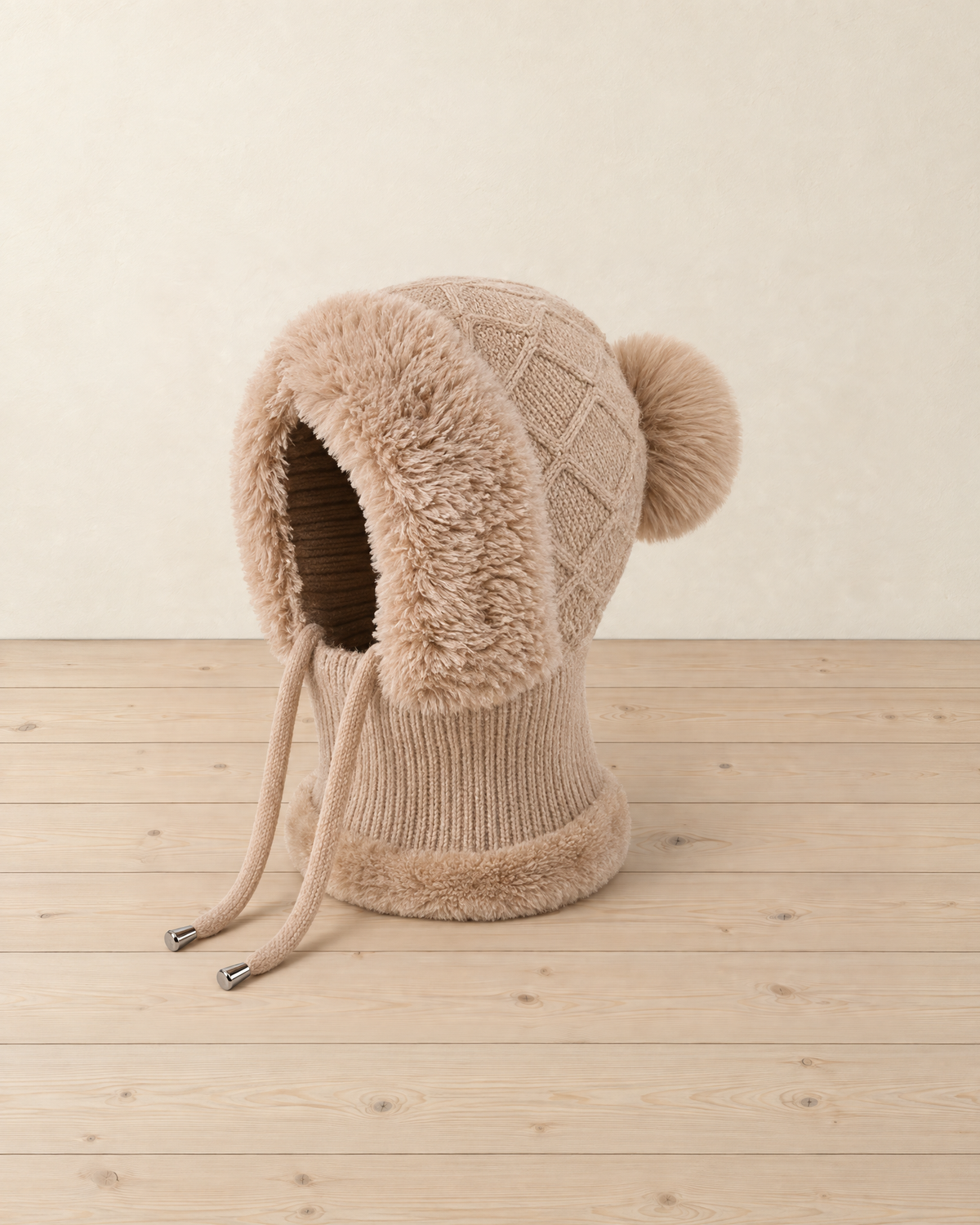 Brown knitted balaclava hood standing upright, faux-fur face surround, diamond-knit crown, pompom and two drawcords