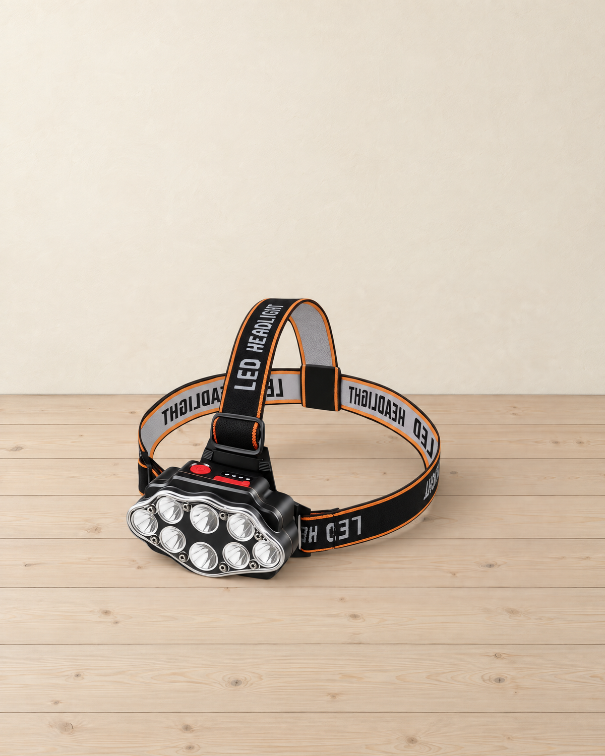 Black rechargeable headlamp with eight round LEDs on a black and orange head strap printed LED HEADLIGHT, on a pale pine floor