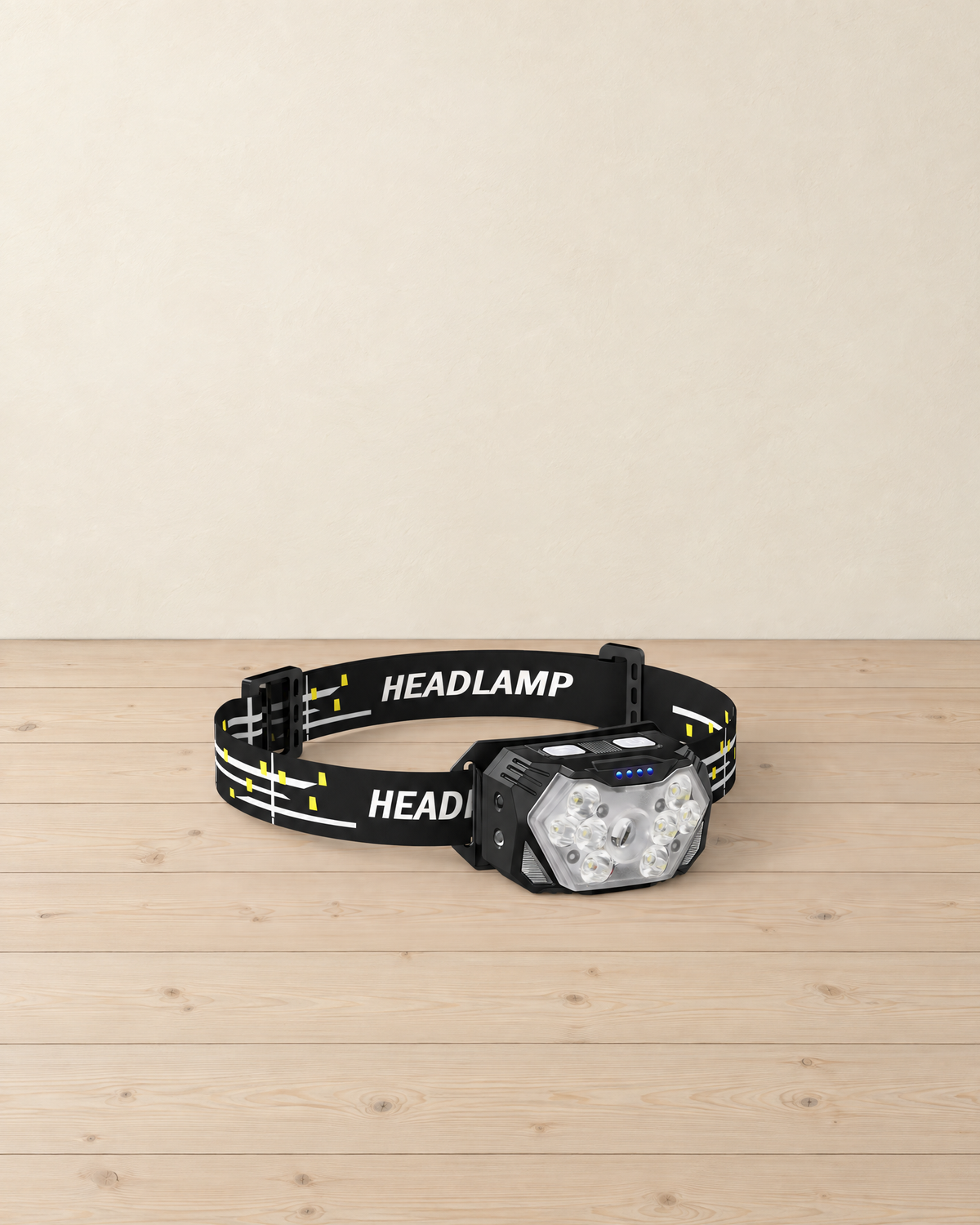 Black 9-LED motion-sensor headlamp on a black headband printed HEADLAMP with white and yellow dashes, on a pale pine floor