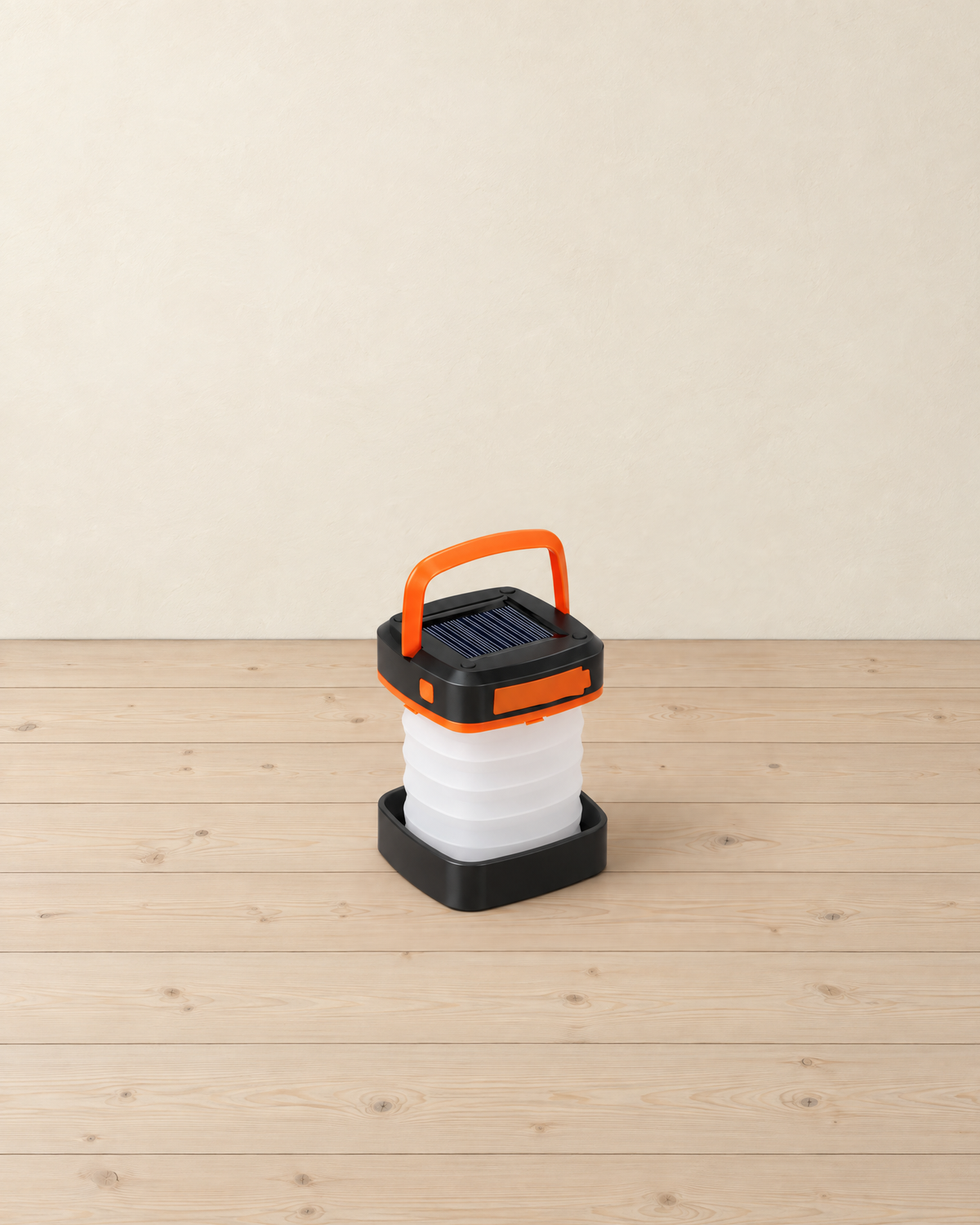 Orange and white collapsible solar camping lantern standing on pale pine floorboards against a cream wall