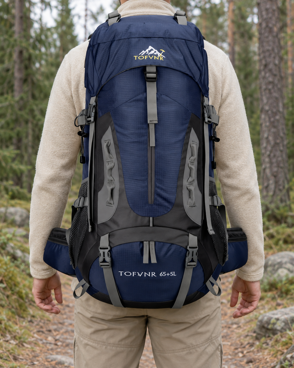 Hiker seen from behind on a forest trail wearing the navy 65 + 5 litre hiking backpack over a cream fleece